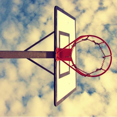 Eski ihmal basketbol Panyası sokak mahkeme yukarıda paslı çember ile. Bckground mavi bulutlu gökyüzü. Retro filtre