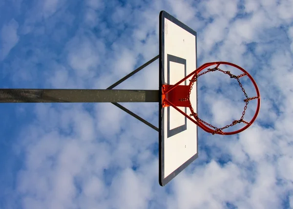 Antiguo tablero de baloncesto descuidado con aro oxidado sobre la cancha de la calle. Cielo nublado azul en bckground. Filtro retro — Foto de Stock