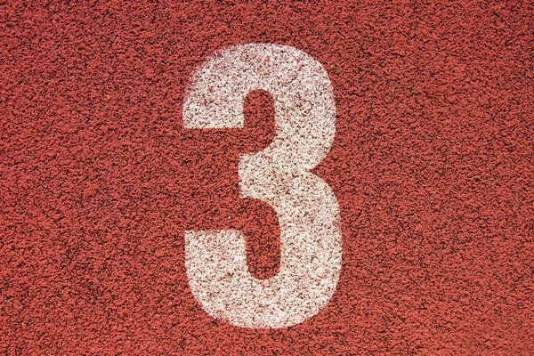 Número de pista branca na pista de corrida de borracha vermelha, textura de pistas de corrida em pequeno estádio ao ar livre — Fotografia de Stock