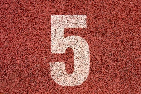 Número de pista branca na pista de corrida de borracha vermelha, textura de pistas de corrida em pequeno estádio ao ar livre — Fotografia de Stock