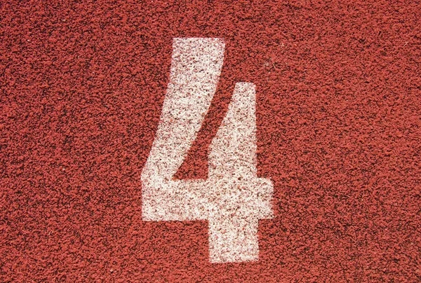 Белый номер трассы на красной резиновой трассе, текстура беговых дорожек на небольшом открытом стадионе — стоковое фото