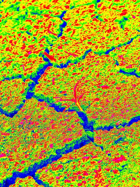 Risse im extrem trockenen Lehm des Feldes. trockener und heißer, leerer Boden. wilde Farben der Thermographie Foto. — Stockfoto