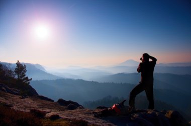 Profesyonel fotoğrafçı kaya tepe üzerinde ayna kamera ile fotoğraf çeker. Rüya gibi adamlara manzara, Bahar Turuncu pembe puslu sunrise.