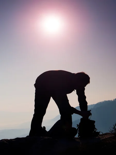 Professionell fotograf förpackning kameran i ryggsäcken på toppen av rock. Drömmande fogy landskap, våren orange rosa dimmiga soluppgång i en vacker dal — Stockfoto