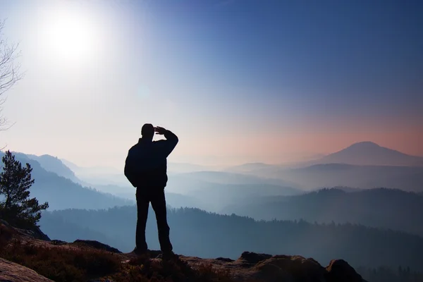 Blue morning. Hiker is standing on the peak of rock in rock empires park and watching over the misty and foggy morning valley to Sun. — Stock Photo, Image