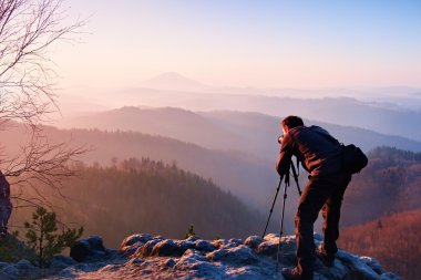 Profesyonel fotoğrafçı kaya tepe üzerinde ayna kamera ile fotoğraf çeker. Rüya gibi adamlara manzara, Bahar Turuncu pembe puslu sunrise bir güzel vadi