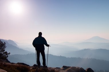 Turizm spor sırt çantası ile oturup kayalık tepe ve puslu Vadisi feryat izlerken. Güneşli sisli gün doğumuna rocky Dağları.