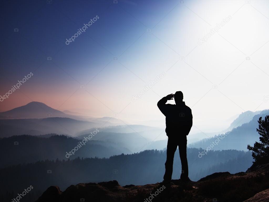 Blue morning. Hiker is standing on the peak of rock in rock empires park and watching over the misty and foggy morning valley to Sun.