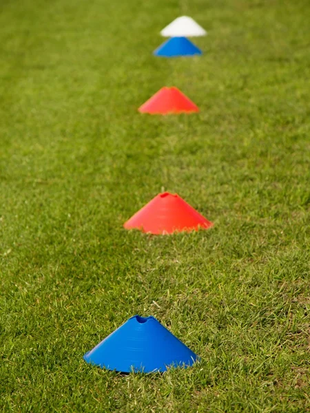 Bunte Kunststoffkegel schaffen Grenzlinie auf Naturfußballplatz. — Stockfoto