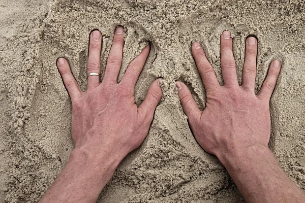 Mão caucasiana masculina na areia salgada na praia . — Fotografia de Stock