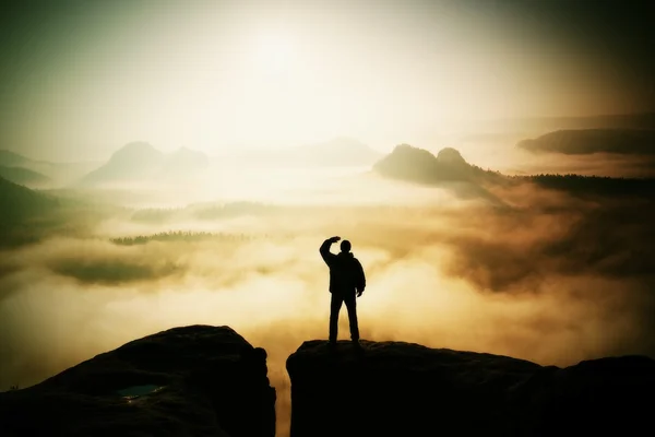 Hermoso momento el milagro de la naturaleza. El hombre se encuentra en el pico de roca arenisca en el parque nacional de Sajonia Suiza y vela por el brumoso y brumoso valle matutino hasta el Sol . —  Fotos de Stock