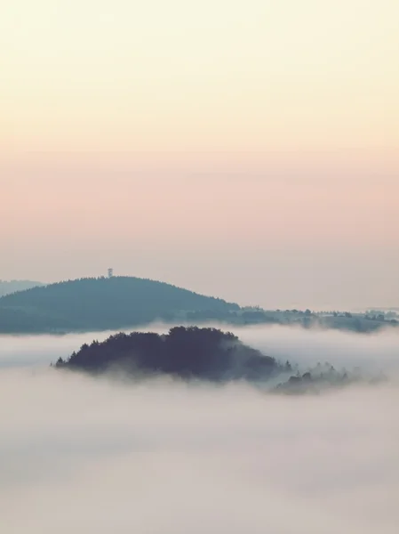 Amanecer brumoso sobre un valle. Las colinas del bosque aumentaron de niebla, la niebla se colorea a azul, oro y naranja . — Foto de Stock
