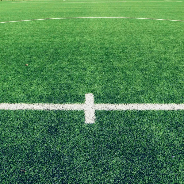 Detail of crossed white lines on outdoor football playground. Detail of lines in a soccer field. Plastic grass and finely ground black rubber. — Stock Photo, Image