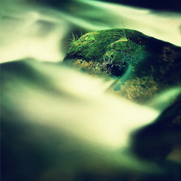 Grandes rocas cubiertas de musgo verde fresco en el agua espumosa del río de montaña. Luz borrosa de agua fría con reflejos, remolinos blancos en rápidos . — Foto de Stock