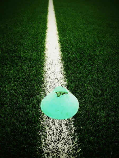 Ljusa gröna blå plast kon på målade vit linje. Plast Fotboll grön torv lekplats med grind svart gummi i kärna. Dramatiska färger. — Stockfoto