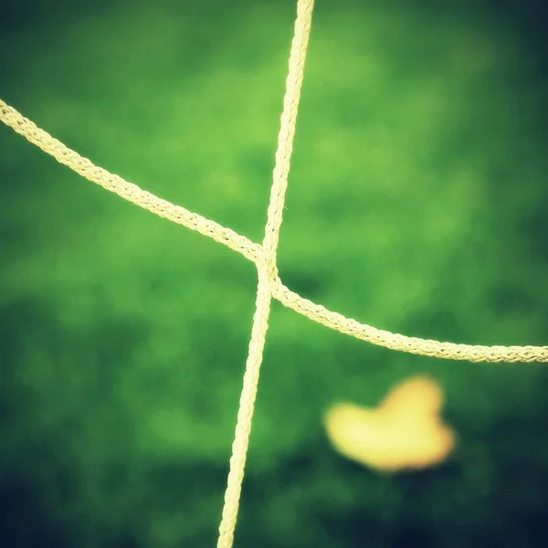 Detail gekreuzter Fußballnetze, Fußball im Tornetz mit Kunststoffrasen auf dem Fußballplatz im Hintergrund — Stockfoto