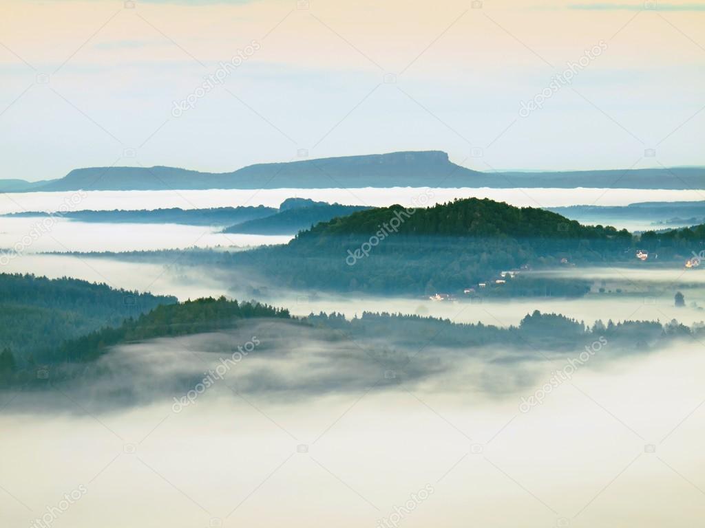 Fall misty valley early morning within sunrise. The fog is moving between hills and peaks of trees a makes with sun rays gentle reflections. Wonderful autumn morning in Bohemian Switzerland.