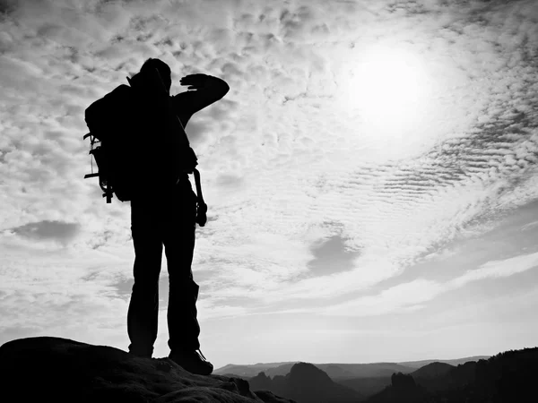 Touristen mit großem Rucksack stehen auf einem felsigen Aussichtspunkt und blicken in ein tiefes nebliges Tal. Sonnenaufgang im Frühling in den felsigen Bergen. — Stockfoto