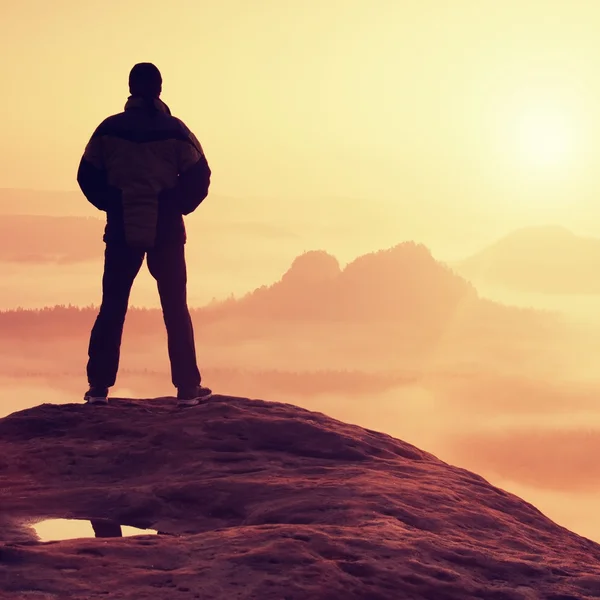 Alone hiker standing on top of a mountain and enjoying sunrise