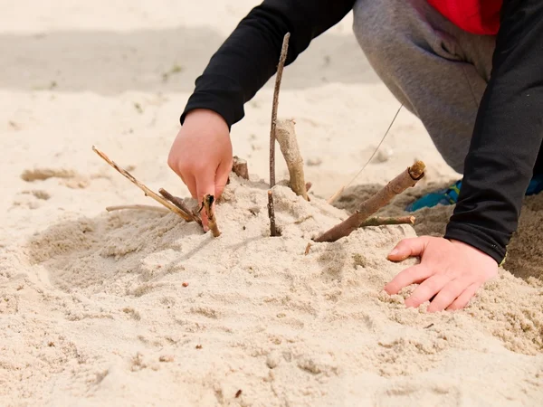 Mão da criança construir fortaleza em areia branca de sal e usar galhos quebrados — Fotografia de Stock