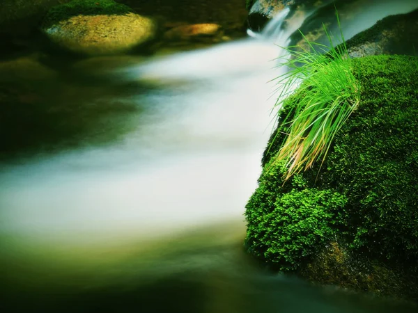 Mountain river with blurred waves of clear water. White curves in rapids between mossy boulders and bubbles create trails. — Stock Photo, Image