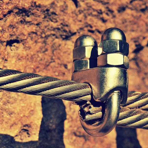 Detalhe de parafusos cromados encaixam ganchos e ilhós em e de corda. Ferro torcido corda fixada em conjunto por parafusos encaixe ganchos. Detalhe da extremidade da corda ancorada na rocha — Fotografia de Stock