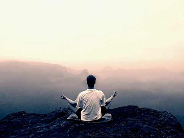 El hombre está haciendo Yoga pose sobre las rocas pico dentro de la mañana brumosa —  Fotos de Stock