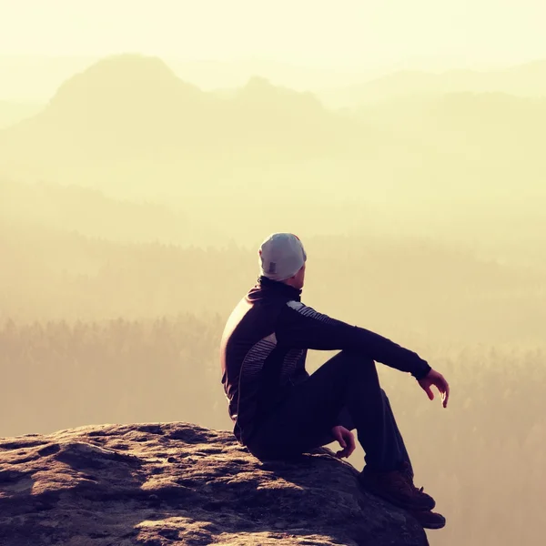 Wanderer sitzt auf einem felsigen Gipfel und genießt die Bergkulisse — Stockfoto