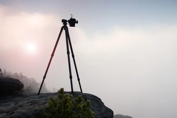 Čedičové stativ s profesionální kamerou na vrcholu připraven k fotografování. Pískovcové vrcholy zvýšil ze zlatých zamlžené pozadí — Stock fotografie