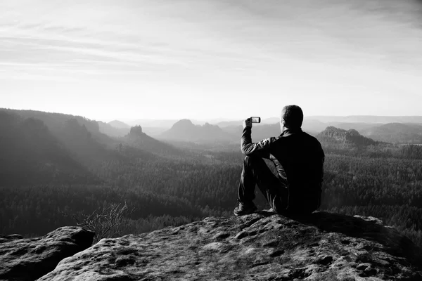 Senderista alto está tomando una foto por teléfono inteligente en la cima de la montaña al amanecer . — Foto de Stock