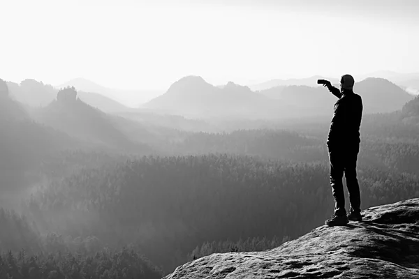 Slim tourist on the sharp peak of rock in rock empires park  is watching over the misty and foggy valley to Sun — Stock Photo, Image
