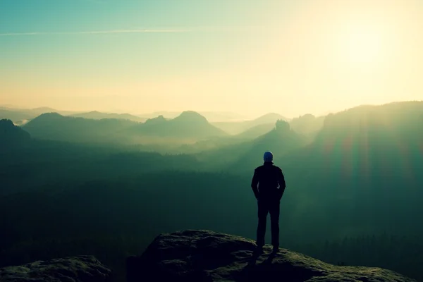 Slim tourist on the sharp peak of rock in rock empires park  is watching over the misty and foggy valley to Sun — Stock Photo, Image