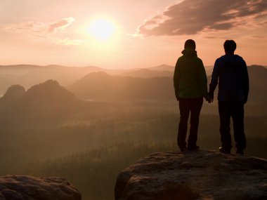 Empires park ve güneş güzel an puslu ve sisli sabah Vadisi'ne üzerinde doğa mucizesi izlemek rock tepe üzerinde elinde yürüyüşçü genç çift el 