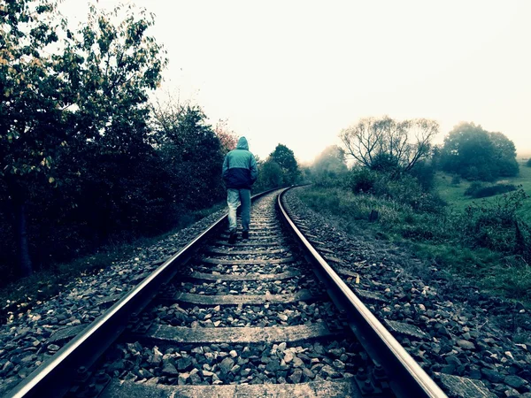 Hunched man is walking on railway in misty autumn day — Stockfoto