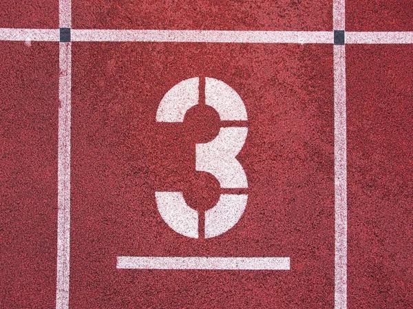 Number three. White track number on red rubber racetrack, texture of running racetracks in athletic stadium — Stock Photo, Image