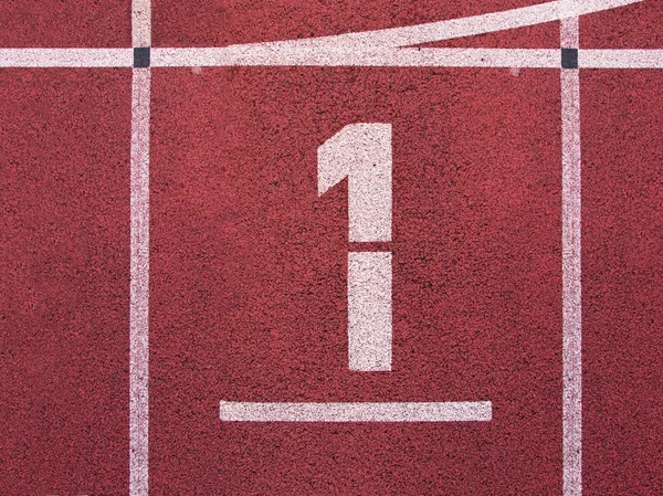 Número uno. Número de pista blanca en pista de carreras de goma roja, textura de pistas de carreras en pequeño estadio al aire libre — Foto de Stock