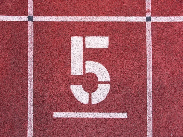 Número cinco. Grande número de pista branca na pista de corrida de borracha vermelha. Corridas de corrida texturizadas suaves no estádio ao ar livre atlético . — Fotografia de Stock