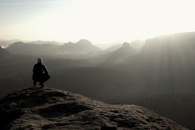 Uzun yürüyüşe çıkan kimse kayalık bir tepe üzerinde oturur ve dağlar sahne tadını çıkarın