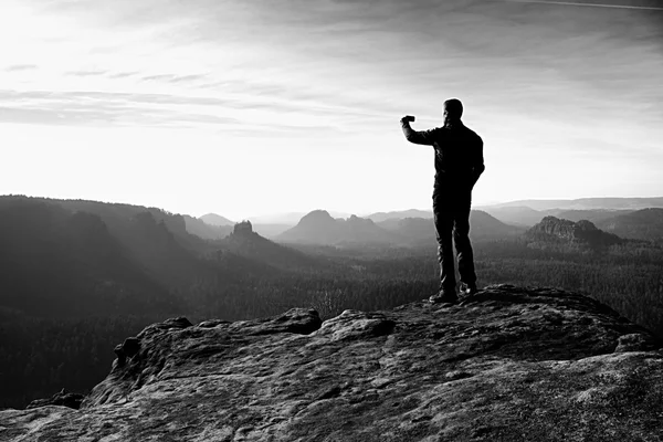 Tall vandrare tar foto på toppen av berget smart telefon på sunrise. — Stockfoto