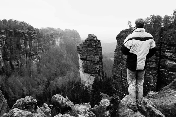 Homem caminhante turístico no pico da rocha em montanhas rochosas — Fotografia de Stock