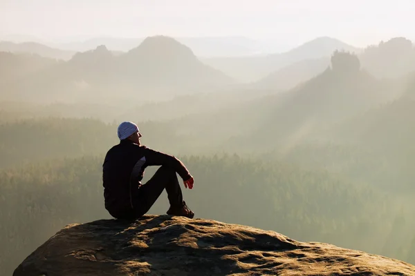 Kletternder erwachsener Mann auf dem Gipfel des Felsens mit wunderschönem Luftbild des tief vernebelten Tales — Stockfoto