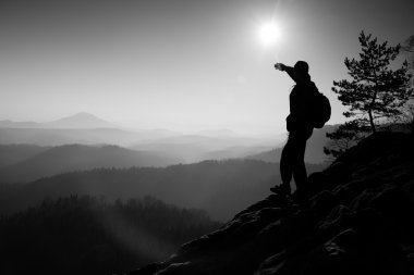 Sunny morning. Hiker is standing on the peak of rock in rock empires park and watch over misty and foggy morning valley