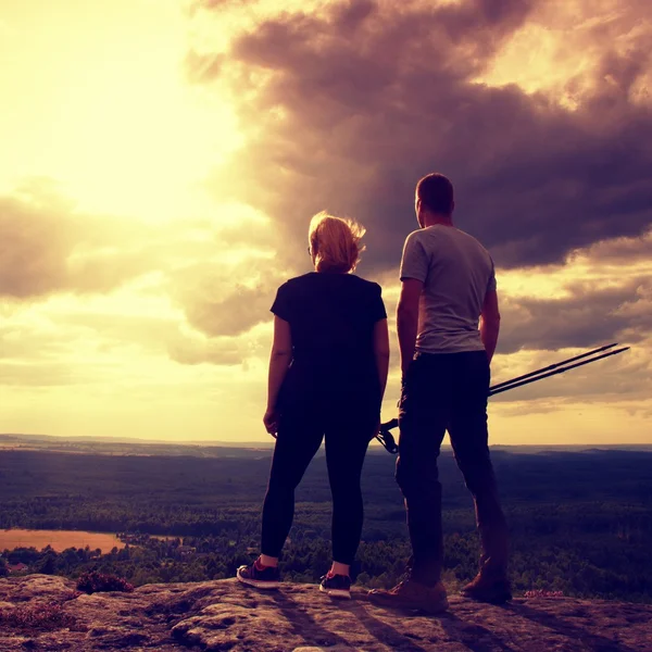 Пара, наслаждающаяся чудесными моментами во время заката. Молодая пара туристов на вершине скалы наблюдают за долиной к Солнцу . — стоковое фото
