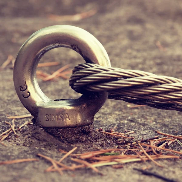 Detail van stalen bout anker oog in rock. De einde knoop van staaldraad. Klimmers pad in rotsen via ferrata. Ijzer twisted touw vast in blok. — Stockfoto