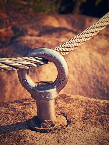 Dettaglio occhio di ancoraggio bullone in acciaio nella roccia arenaria. Il nodo terminale di corda d'acciaio. Sentiero arrampicatori via ferrata. Corda ritorta di ferro fissata in blocco . — Foto Stock