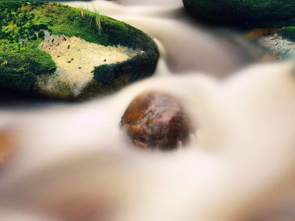 Mountain river with blurred waves of clear water. White curves in rapids between mossy boulders and bubbles create trails. — Stock Photo, Image