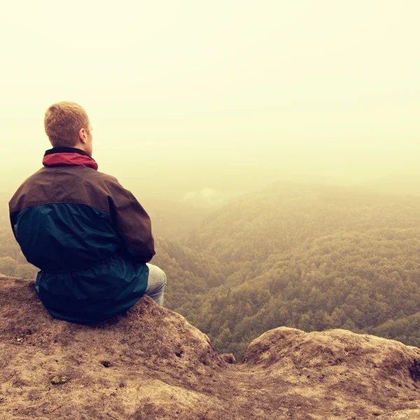 Melancholischer und trauriger Tag. Mann am Fels über tiefem Tal. Touristen auf dem Gipfel des Sandsteinfelsens beobachten den Nebel. — Stockfoto