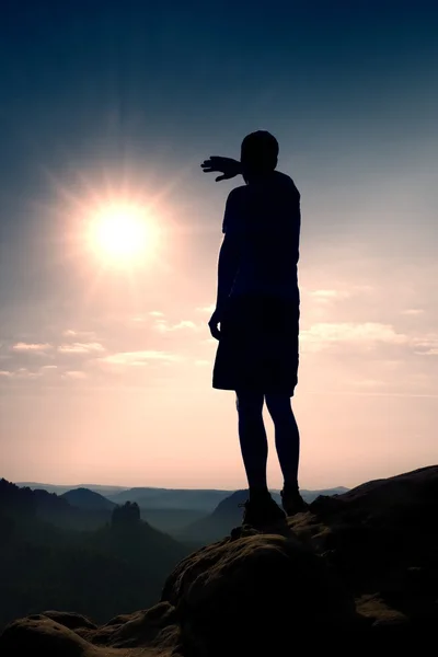 Turista magro em calças no penhasco do império do rock está assistindo ao sol quente acima . — Fotografia de Stock