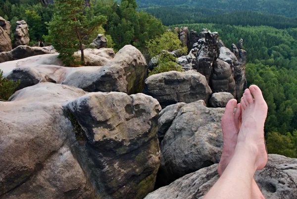 Naked male sweaty long legs on peak of sharp rock above valley. — Stock Photo, Image