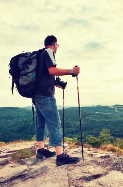 Fotoğrafçı büyük ayna kamera boyun ve sırt çantası ile kaya tepe üzerinde kal. Dağlık manzara, taze yeşil renk Vadisi.